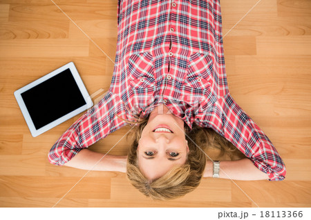 Smiling woman lying on floor next to tablet Smiling woman lying on floor next to tablet 18113366