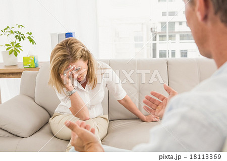 Unhappy woman sitting on couch and talking to therapist 18113369