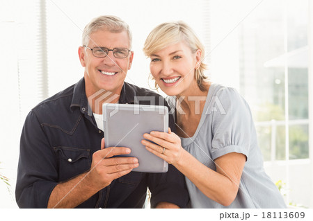 Smiling business team working over a tablet Smiling business team working over a tablet 18113609