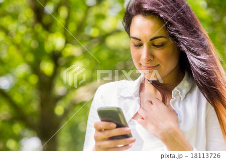 Beautiful brunette in the park sending text Beautiful brunette in the park sending text 18113726