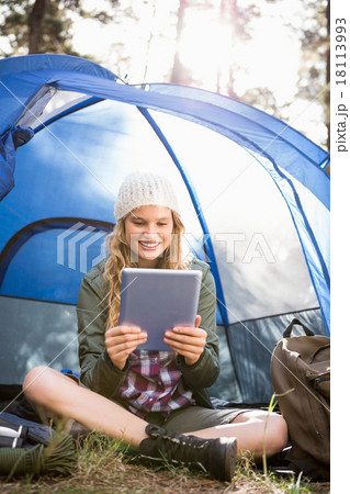 Pretty blonde camper using tablet and sitting in tent Pretty blonde camper using tablet and sitting in tent 18113993