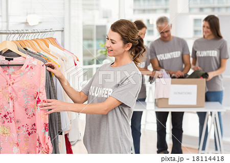 Smiling female volunteer choosing clothes 18114418