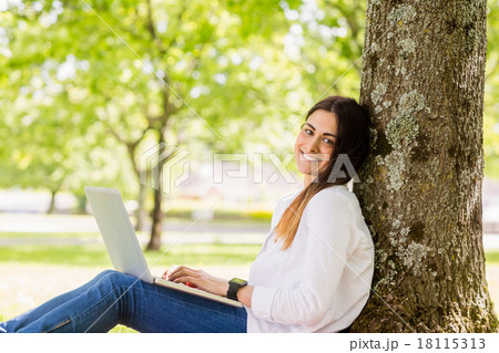 Beautiful brunette using laptop in the park 18115313