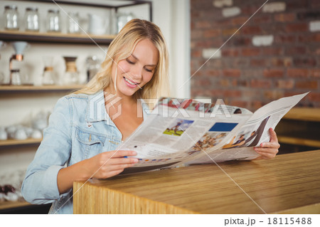 Smiling blonde reading newspaper Smiling blonde reading newspaper 18115488