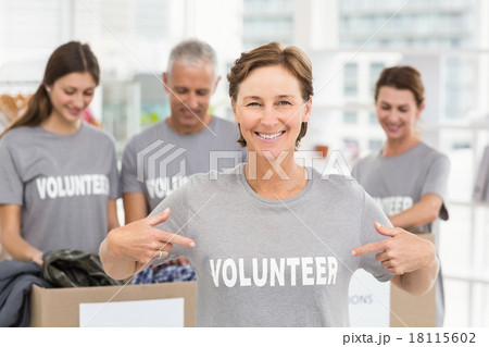 Smiling female volunteer pointing on shirt Smiling female volunteer pointing on shirt 18115602