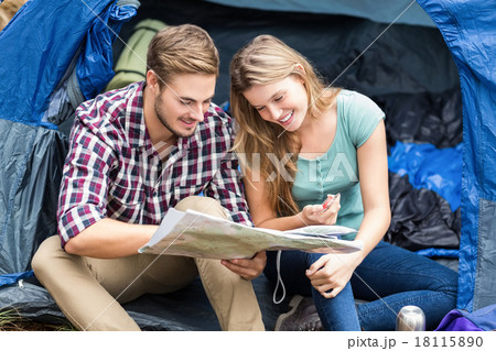 Young pretty hiker couple sitting in a tent looking at map Young pretty hiker couple sitting in a tent looking at map 18115890