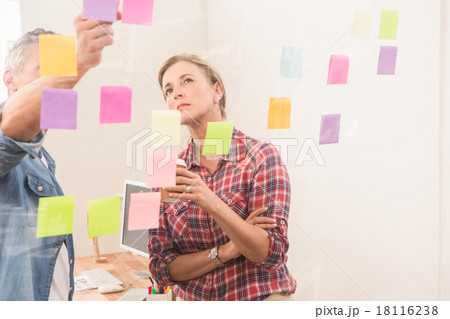 Casual business colleagues working with sticky notes Casual business colleagues working with sticky notes 18116238