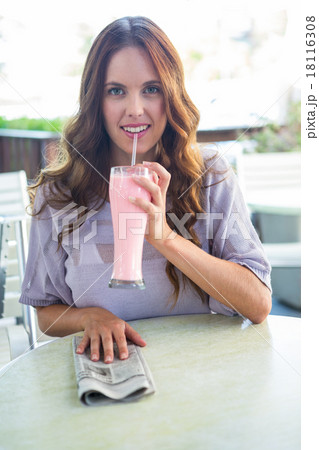 Pretty woman sipping smoothie outside at cafe 18116308