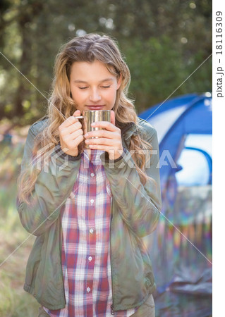 Pretty blonde camper enjoying beverage in front of tent 18116309