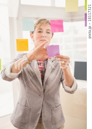 Casual businesswoman putting sticky notes on glass Casual businesswoman putting sticky notes on glass 18117321