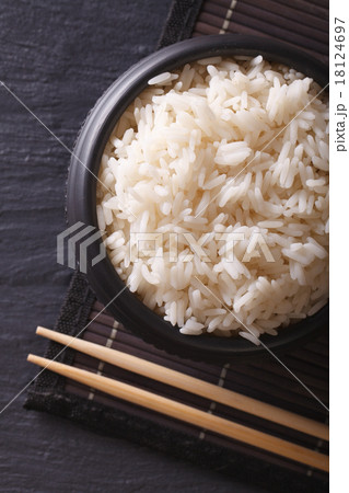 White rice in a black bowl and chopsticks top view 18124697