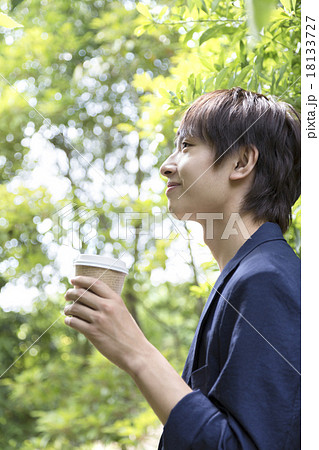 コーヒーカップを持つ若者男性の写真素材