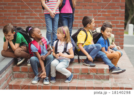 Cute pupils sitting on steps outside 18140298