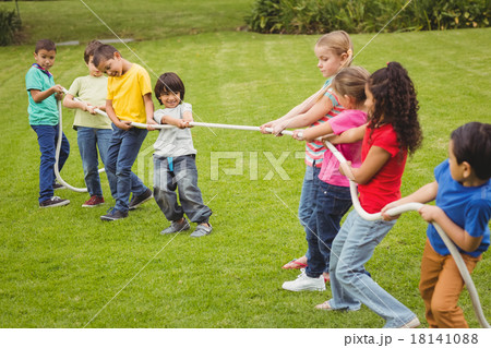 Cute pupils playing tug of war on the grass outside 18141088