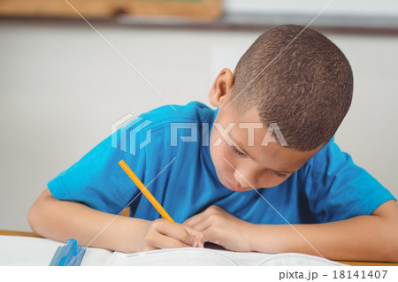 Concentrated pupil working at his desk in a classroom Concentrated pupil working at his desk in a classroom 18141407