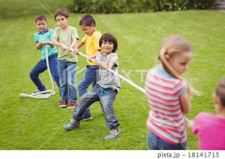 Cute pupils playing tug of war on the grass outside 18141715