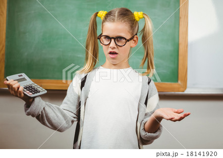 Confused cute pupil holding calculator in a classroom 18141920