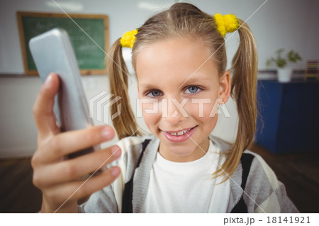 Cute pupil using smartphone in a classroom Cute pupil using smartphone in a classroom 18141921
