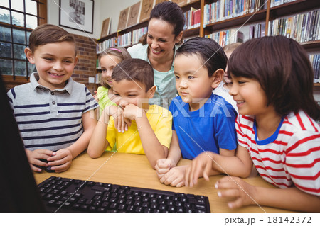 Pupils and teacher in the library using computer 18142372