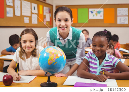 Teacher and pupils smiling at camera in classroom 18142500