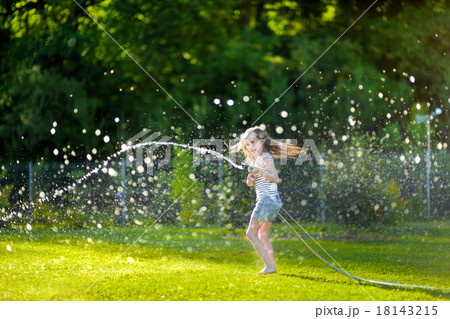 Adorable little girl playing with a garden hose 18143215