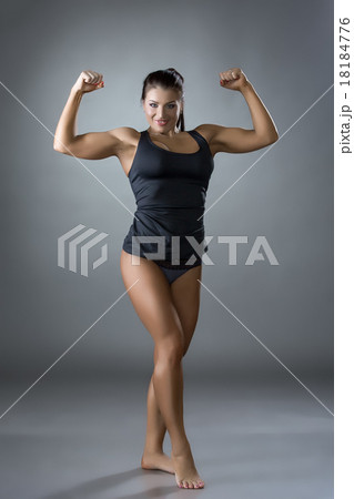 Muscular woman posing in studio, on gray backdrop 18184776