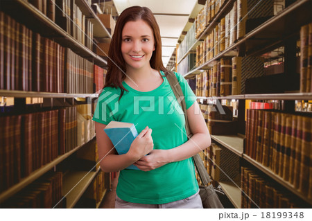Composite image of student smiling at camera in library 18199348