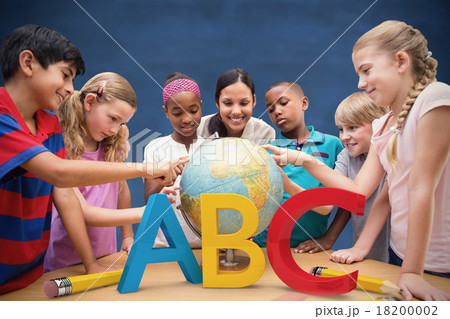 Composite image of cute pupils and teacher looking at globe in l 18200002