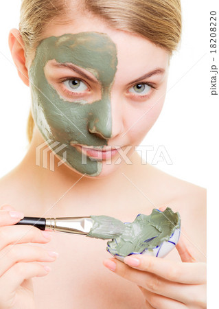 Girl applying facial clay mask to her face Girl applying facial clay mask to her face 18208220