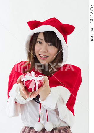 クリスマスの衣装を着て笑顔でプレゼントを渡す女子高校生 縦構図 学生 イベント イメージの写真素材