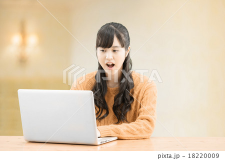 セータを着てシンプルな室内に座っているロングヘアーの10代の女性 18220009