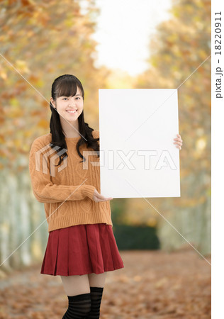 秋の枯れ葉の綺麗な並木道に立っている10代の女性 18220911