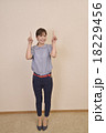 両手で上を指し示しす若い女性 18229456