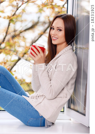 Woman on the windowsill with a cup of drink. 18231925