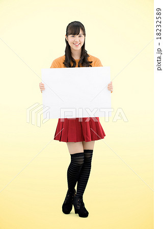 セーターを着てボードを持って立っている若い女性の全身のポーズ 18232589