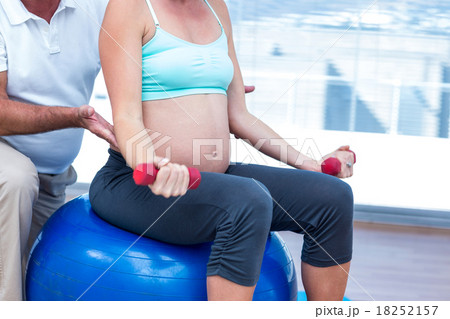 Mid section of pregnant woman exercising Mid section of pregnant woman exercising 18252157