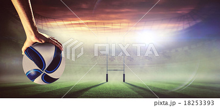 Composite image of rugby player with arm raised holding ball Composite image of rugby player with arm raised holding ball 18253393
