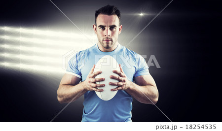 Composite image of rugby player looking at camera with ball 18254535