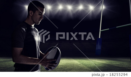 Composite image of calm rugby player thinking while holding ball 18255294
