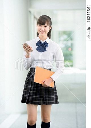 建物の中に立っている制服姿の女子高校生のポーズイメージの写真素材