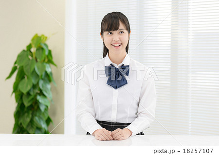 白いテーブルの前に座っている制服姿の女子高生の写真素材