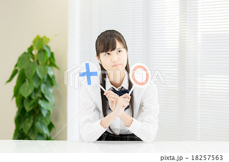 白いテーブルの前に座っている制服姿の女子高生 18257563