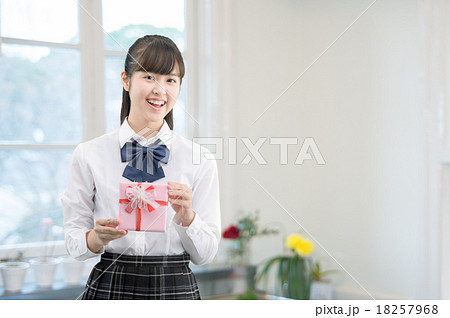 キッチンにプレゼントを持って立っている制服姿の女子高生 18257968