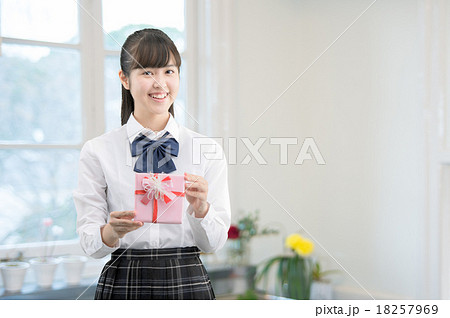 キッチンにプレゼントを持って立っている制服姿の女子高生 18257969