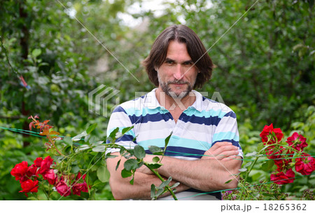 A man near the flowerbeds in the garden 18265362