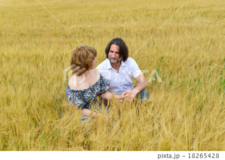 Loving middle-aged couple standing in field in summer Loving middle-aged couple standing in field in summer 18265428
