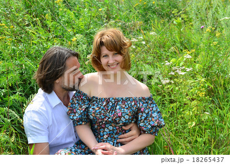 loving couple sitting on the grass in summer loving couple sitting on the grass in summer 18265437