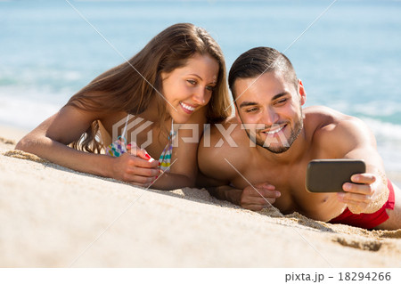 Happy couple taking photo on the beach Happy couple taking photo on the beach 18294266