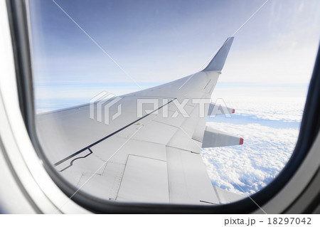 飛行機の窓から見える空と雲のカーペットの写真素材