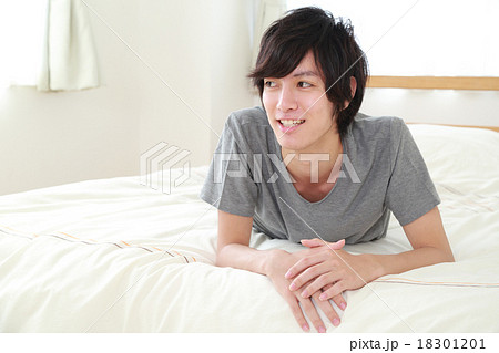 ベッドに寝そべる若い男性の写真素材 1011
